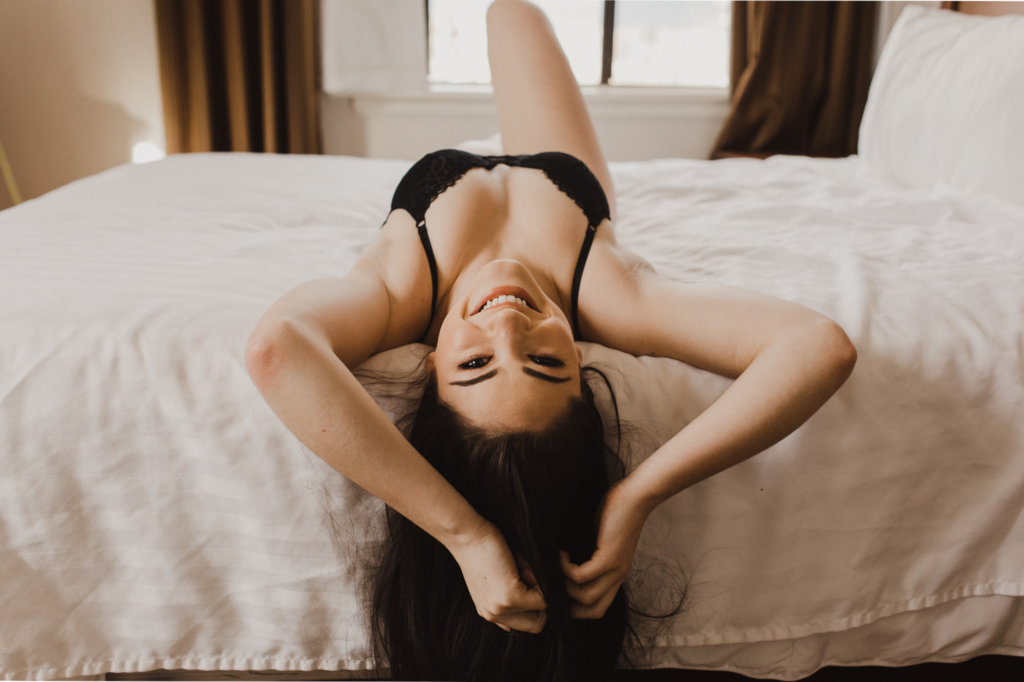 Uśmiechnięta kobieta leżąca na łóżku w czarnej bieliźnie