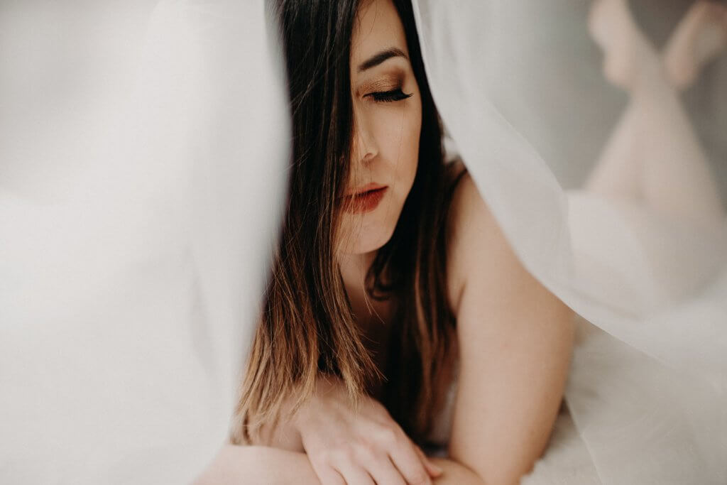 Kobieta leżąca na łóżku w bieliźnie z zamkniętymi oczami 