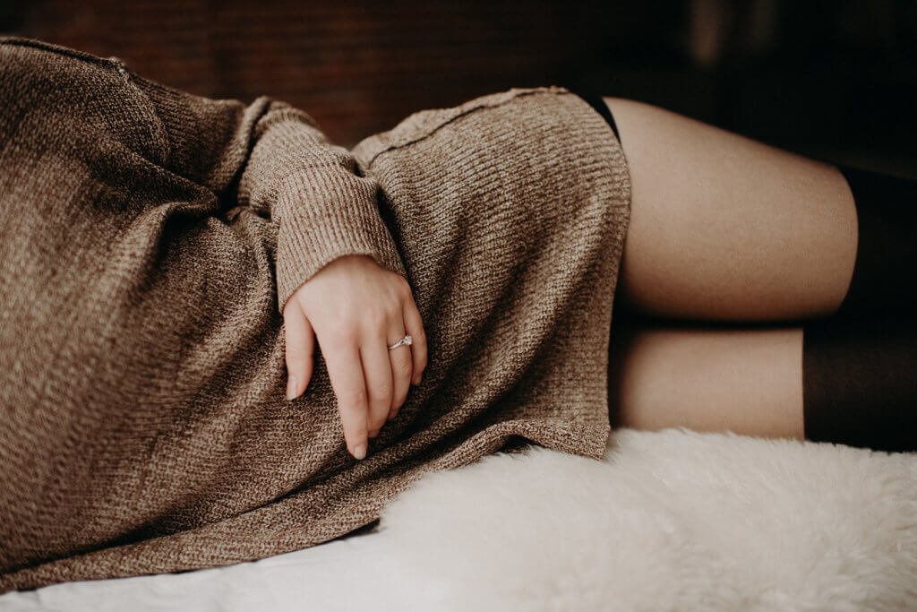 Kobieta leżąca na boku w swetrze i pończochach 