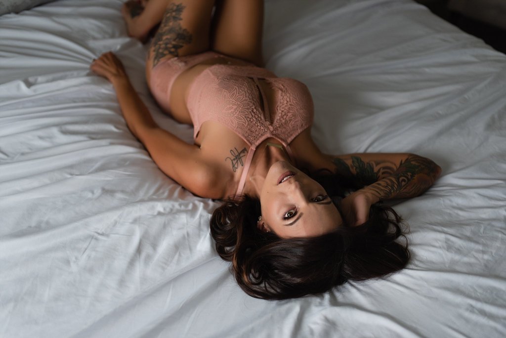Kobieta z tatuażami leżąca na łóżku w bieliźnie