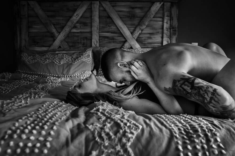 Kobieta i mężczyzna leżący na łóżku w bieliźnie całują się