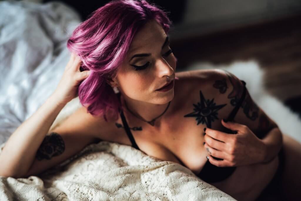 Kobieta z fioletowymi włosami, kolczykiem w nosie i tatuażami w bieliźnie